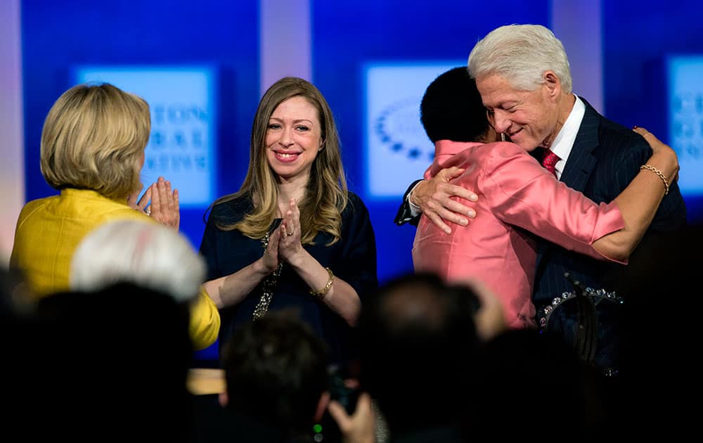Former US President Bill Clinton embraces global citizen award recipient, Graca Machel, wife of former South African President Nelson Mandela, as Chelsea Clinton and Hilary Clinton stand on the stage during the closing session of the Clinton Global Initiative in New York.