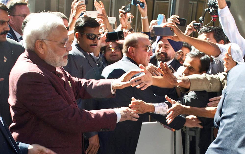 Prime Minister Narendra Modi greets people outside his hotel upon his arrival.