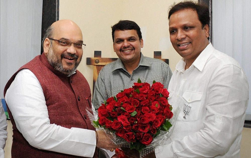 BJP President Amit Shah being welcomed by the partys Mumbai President Ashish Shelar as State President Devendra Fadnavis looks on in Mumbai .