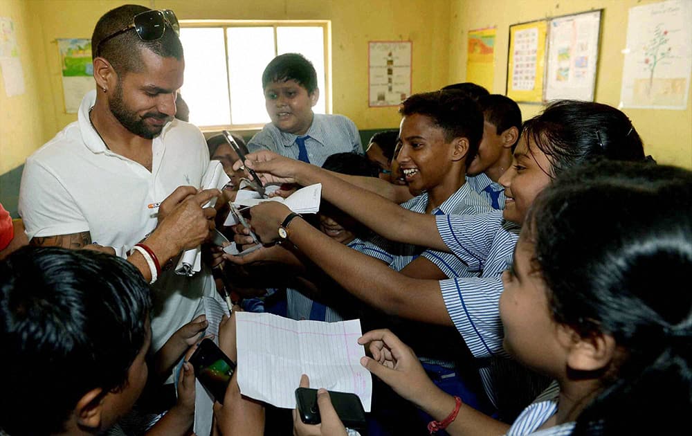 Cricketer Shikhar Dhawan signing autographs for students during his visit to a school in Kolkata.