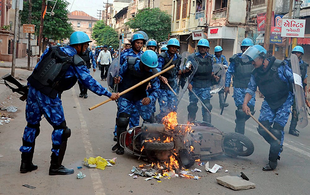 RAF personnel try to douse fire on a scooter following fresh communal violence in Vadodara.