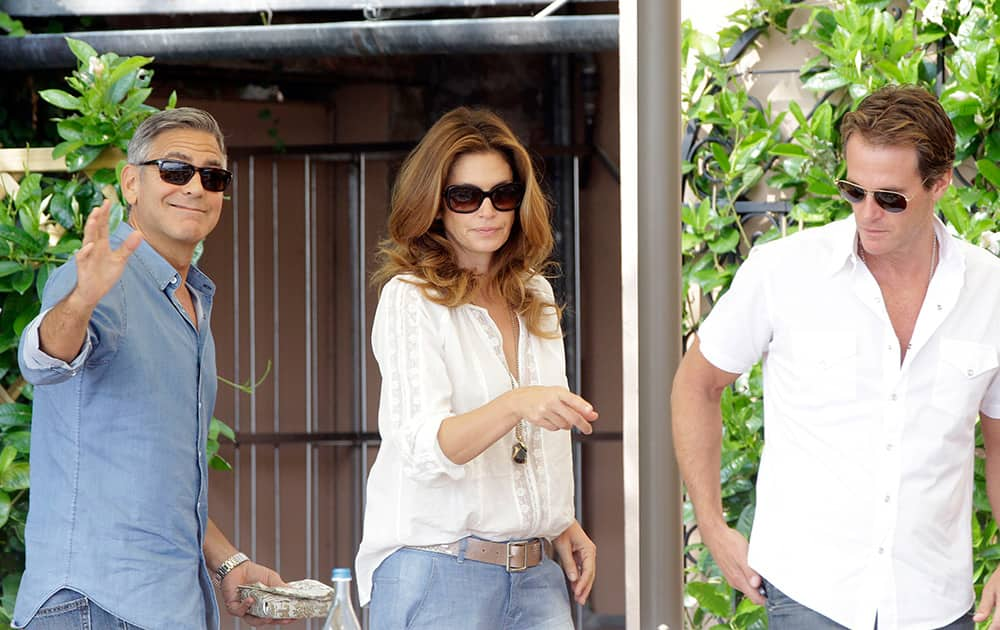 George Clooney, left, Cindy Crawford and her husband Rande Gerber walk in the garden of the Cipriani hotel in Venice.