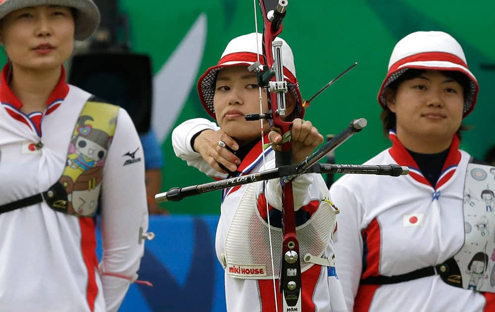 Kaori Kawanaka of Japan competes as her team mates Ren Hayakawa and Yuki Hayashi look on during their Recurve Women's Team archery bronze medal match against India at the 17th Asian Games at Gyeyang Gymnasium in Incheon, South Korea.