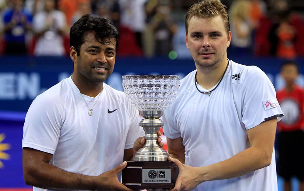 Leander Paes, left, of India and Marcin Matkowski of Poland pose with their trophy after winning their men's doubles final match against Jamie Murray of Britain and John Peers of Australia at the Malaysian Open tennis tournament.