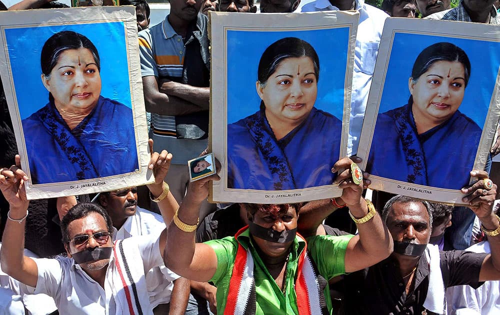 Supporters of AIADMK Supremo J Jayalalithaa hold her posters as they sit on a fast in protest against her conviction in a disproportionate assets case by a court, in Chennai.