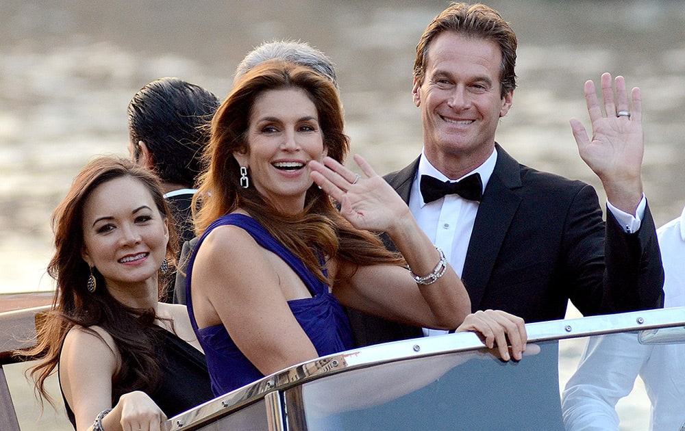 Cindy Crawford and Rande Gerber wave from a boat as they go to George Clooney's wedding with Amal Alamuddin, in Venice, Italy.