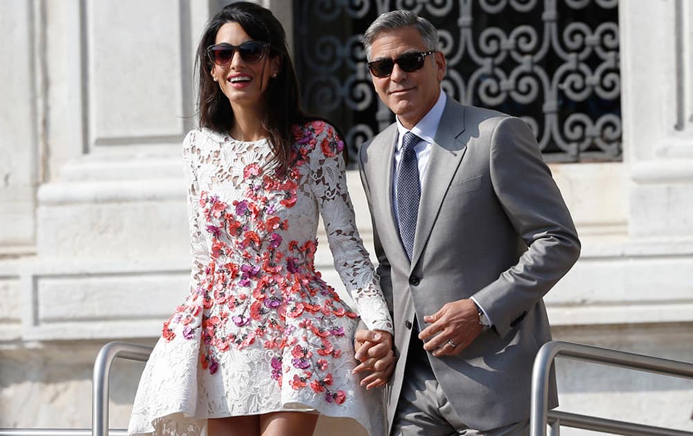 George Clooney is flanked by his wife Amal Alamuddin as they leave the Aman luxury Hotel in Venice, Italy.