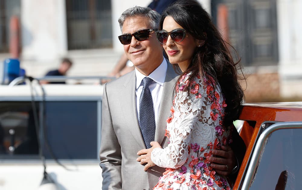 George Clooney is flanked by his wife Amal Alamuddin as they leave the Aman luxury Hotel in Venice, Italy.