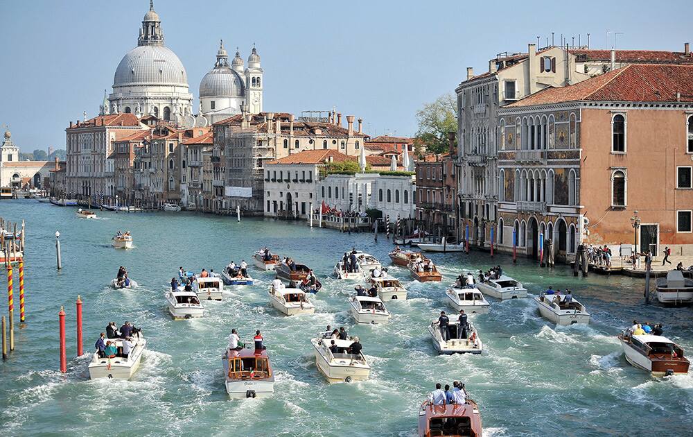 The boat carrying George Clooney and his wife Amal Alamuddin, is surrounded by media and security boats as they cruise the Grand Canal after leaving the Aman luxury Hotel in Venice, Italy.