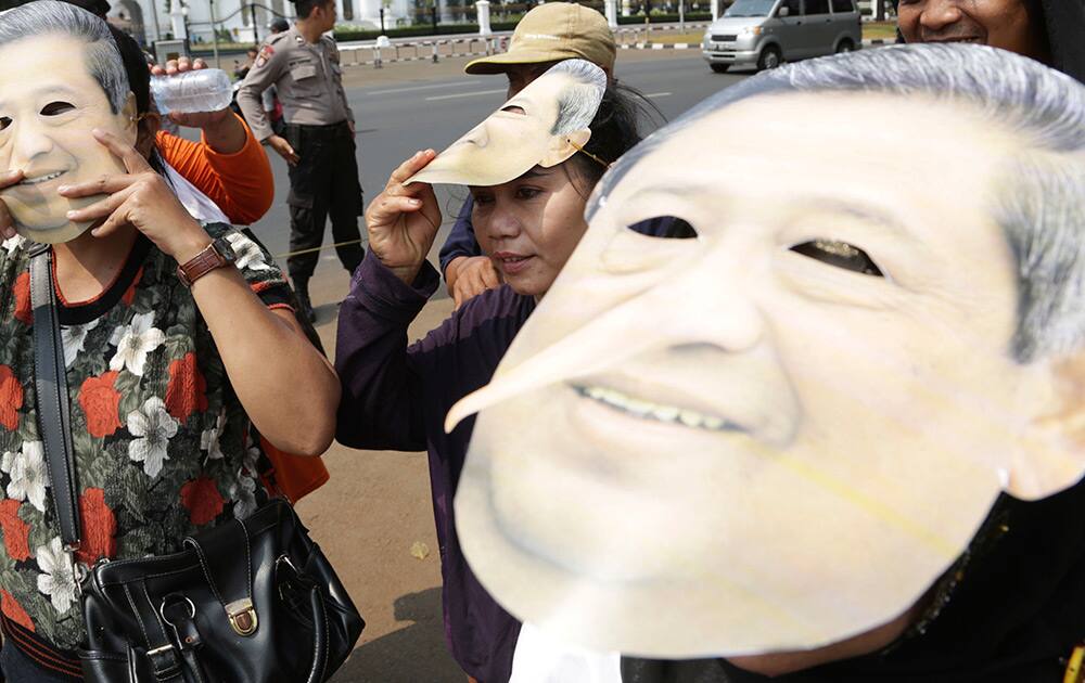 Protesters wear a mask of Indonesia president Susilo Bambang Yudhoyono with long nose during a rally, opposing a regional election bill in front of palace in Jakarta.