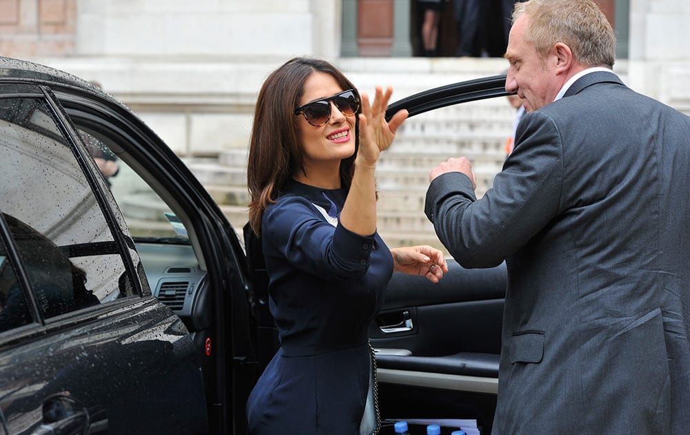 Mexican actress Salma Hayek waves as her husband Francois-Henri Pinault, CEO of luxury group Kering, looks on after Stella McCartney's Spring/Summer 2015 ready-to-wear fashion collection presented in Paris, France.