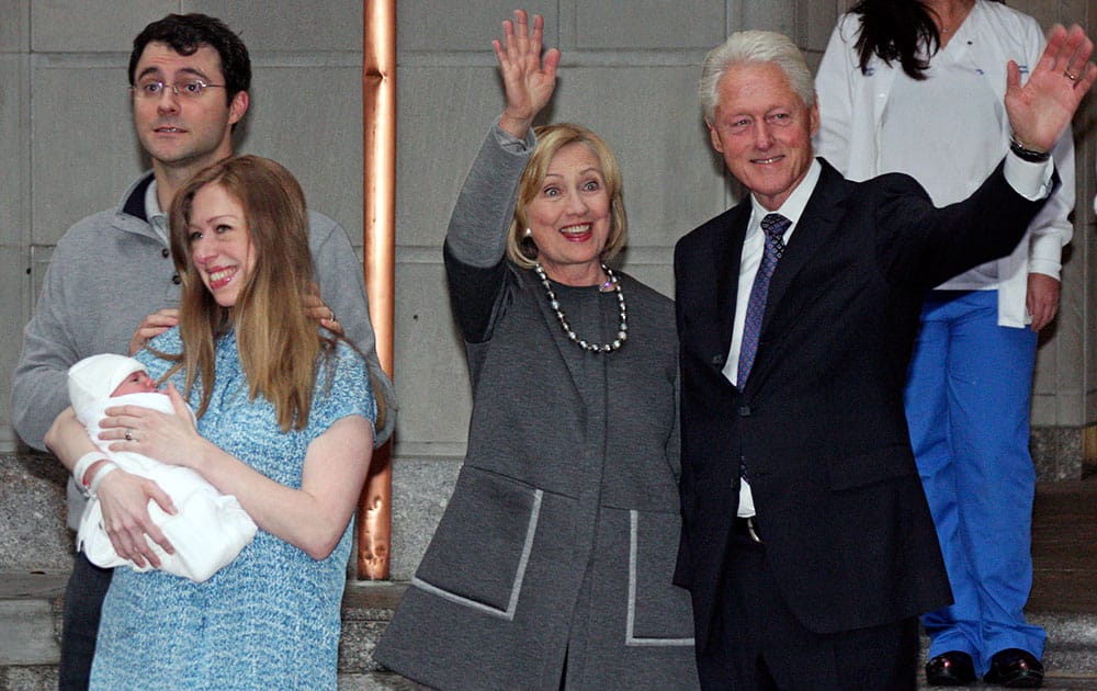 Former President Bill Clinton, right, and former Secretary of State Hillary Rodham Clinton, second from right, wave to the media as Marc Mezvinsky and Chelsea Clinton pose for photographers with their newborn baby, Charlotte, after the family leaves Manhattan's Lenox Hill hospital in New York.