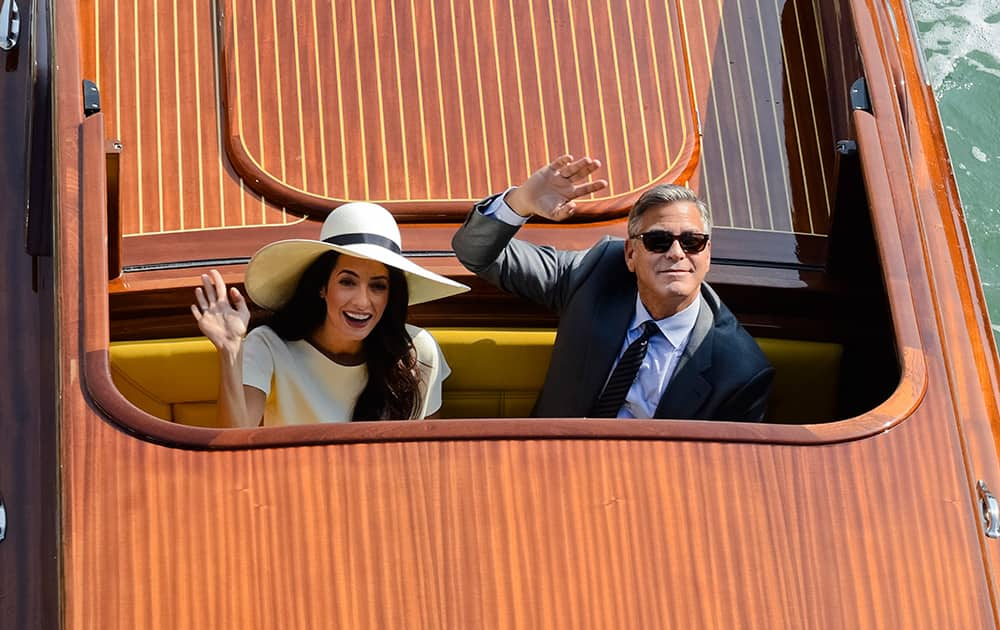 Actor George Clooney and Amal Alamuddin wave from a boat as they leave after a civil weeding ceremony at the town hall in Venice, Italy.