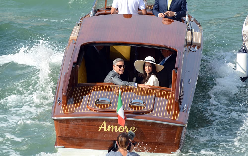 George Clooney, flanked by his wife Amal Alamuddin, sit on a water-taxi after leaving the city hall in Venice, Italy.