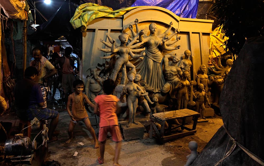 Children play in an alley beside idols of Hindu goddess Durga being prepared ahead of the Durga Puja festival at Kumartuli or potters' place in Kolkata.