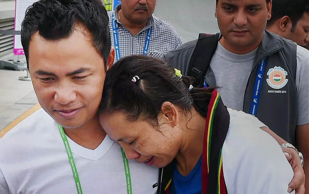 Indian Boxer Lalshram Sarita Devi being consoled by her husband after she was knocked out of the 60 kg boxing semifinal bout against Korea at the Asian Games in Incheon on Tuesday. Sarita Devi controversially settled for a bronze medal after losing her bout against South Koreas Jina Park despite a dominating performance which left the home favourite with a bloodied nose.