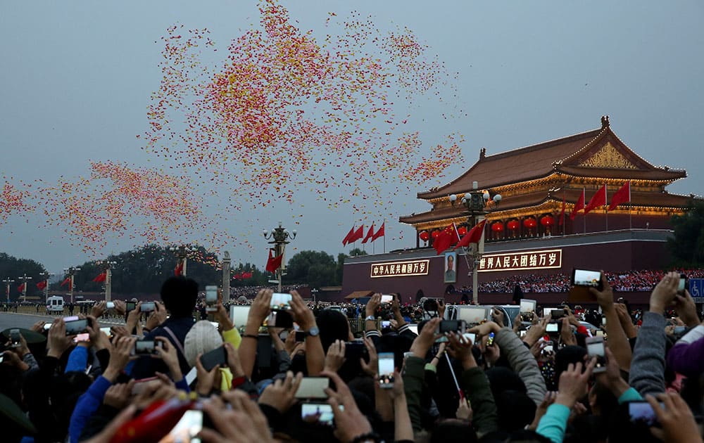 People use their smartphones to film the balloons released near Tiananmen Gate after the flag raising ceremony on the National Day, the 65th anniversary of the founding of the People's Republic of China, in Beijing.