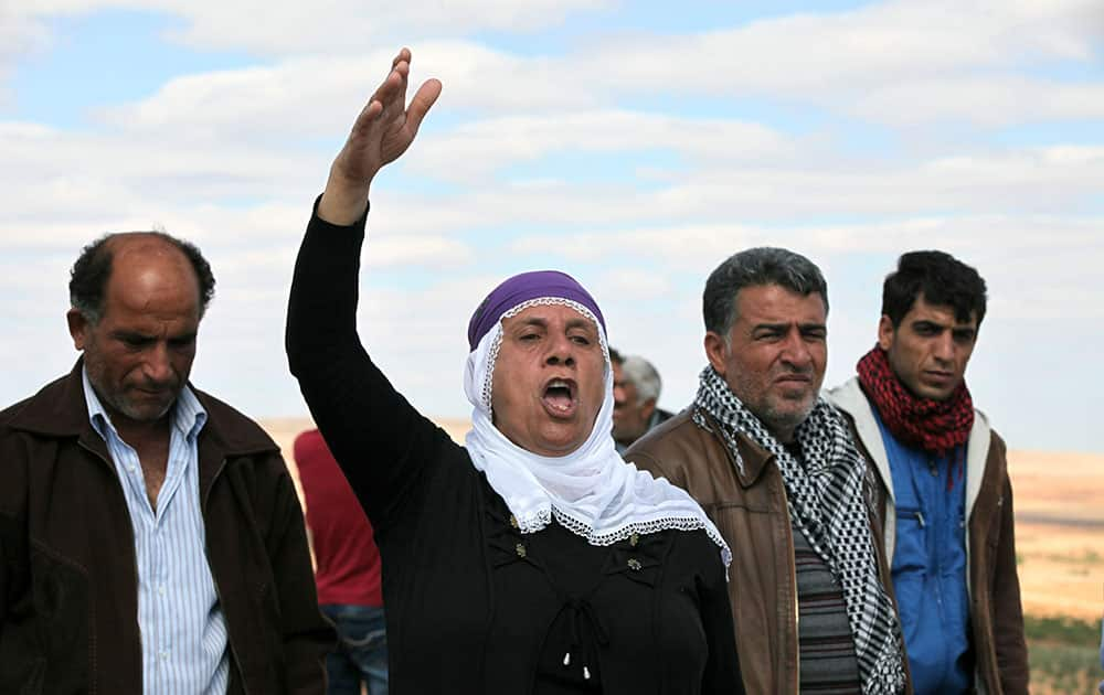 A woman shouts slogans as Turkish Kurds watch the fighting between Islamic militants and Kurdish forces to the west of Kobani, Syria, at the Turkey-Syria border near Suruc, Turkey.