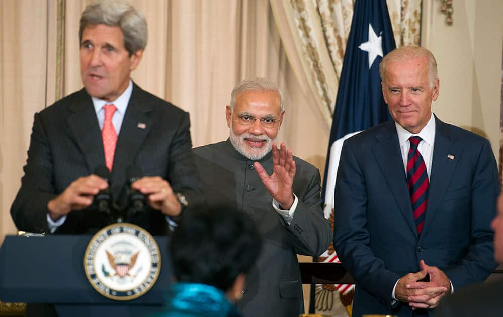 Indian Prime Minister Narendra Modi, flanked by Secretary of State John Kerry and Vice President Joe Biden, waves to a person in the audience during a luncheon at the State Department in Washington