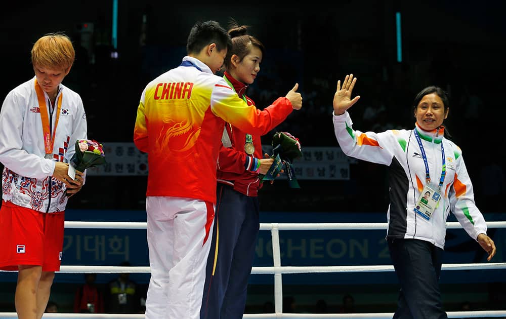 India's L. Sarita Devi, right, waves and leaves the podium, as gold medallist China's Yin Junhua gestures to her watched by bronze medalist Vietnam's Thi Duyen Luu, and silver medallist South Korea's Park Ji-na stands by the side, after Devi refused her bronze medal during the medal ceremony for the women’s light 60-kilogram division boxing at the 17th Asian Games in Incheon, South Korea.