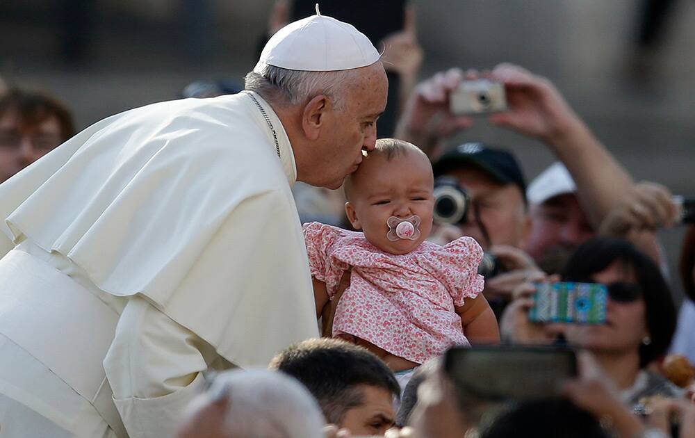 Pope Francis kisses a baby upon his arrival in St. Peter's Square on the occasion of the weekly general audience at the Vatican.