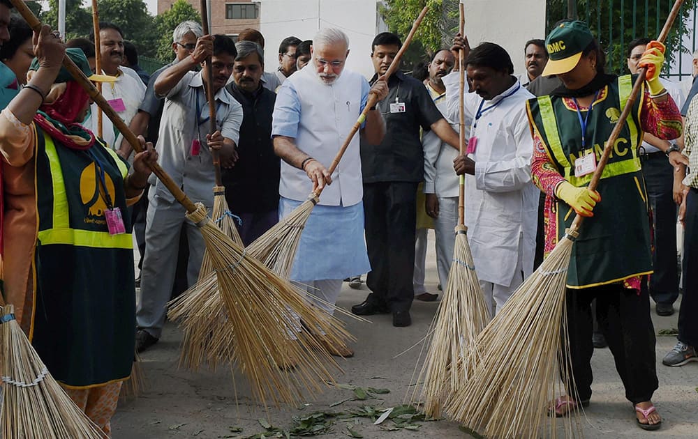 Prime Minister Narendra Modi wields a broom with NDMC workers to launch Swachh Bharat Abhiyan in Valmiki Basti in New Delhi.