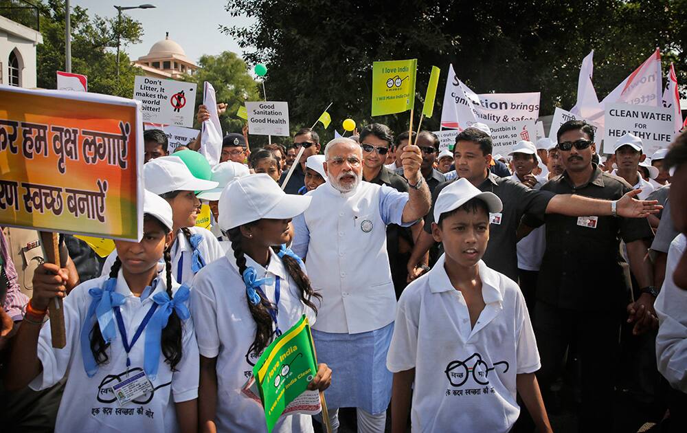 Prime Minister Narendra Modi, centre, waves a flag as he joins school children in a walkathon as part of launching a nationwide cleanup campaign in New Delhi.