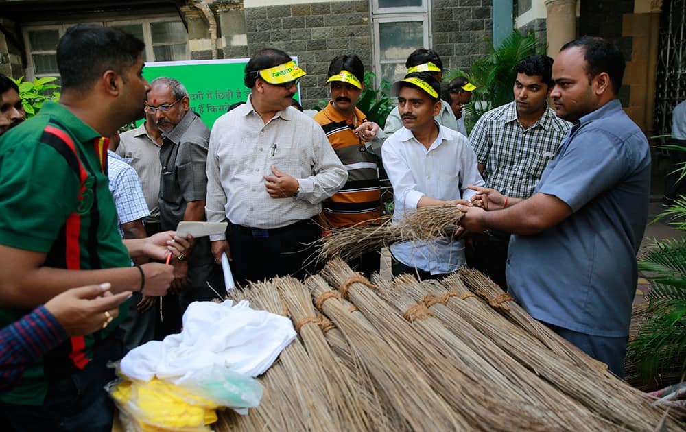 Railways employees distribute brooms to clean their office in Mumbai.