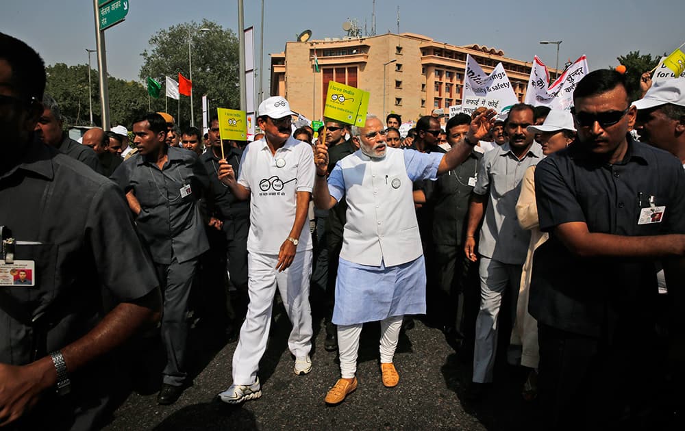 Prime Minister Narendra Modi, centre, waves a flag as he joins others in a walkathon as part of launching a nationwide cleanup campaign in New Delhi.