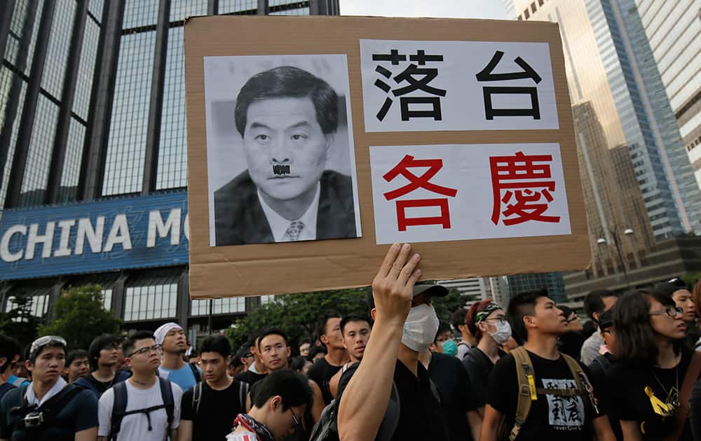 Protesters raises a placard with a deface picture of Hong Kong's Chief Executive Leung Chun-ying outside a flag-raising ceremony where Hong Kong's embattled leader attended in Hong Kong.
