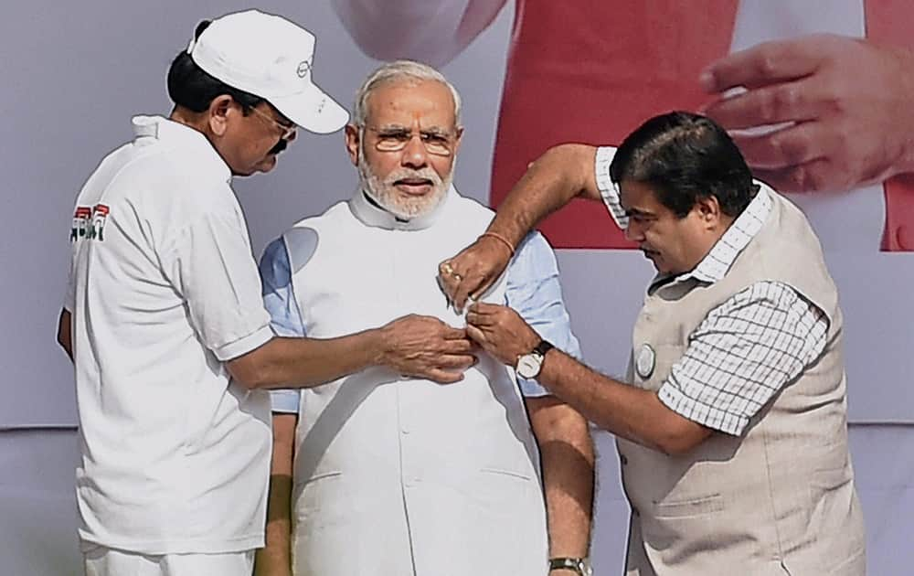 Union ministers Nitin Gadkari and M Venkaiah pinning a badge on Prime Minister Narendra Modis jacket during the launch of nationwide cleanliness campaign, the Swachh Bharat Mission at Rajpath in New Delhi.