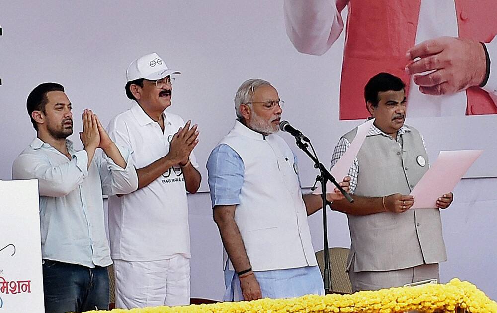 Prime Minister Narendra Modi, flanked by Union ministers Venkaiah Naidu and Nitin Gadkari and actor Aamir Khan, takes pledge for cleanliness during the launch of the nationwide campaign, the Swachh Bharat Mission at Rajpath in New Delhi.