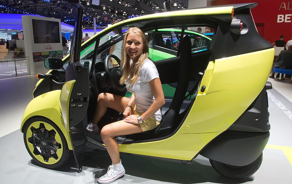 A hostess get out of a Toyota i - Road electric car during the press day at the Motor Show in Paris, France.