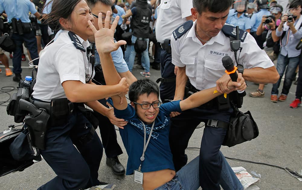 A pro-democracy protester is taken away by police offers as an ambulance tries to leave the compound of the chief executive office in Hong Kong.