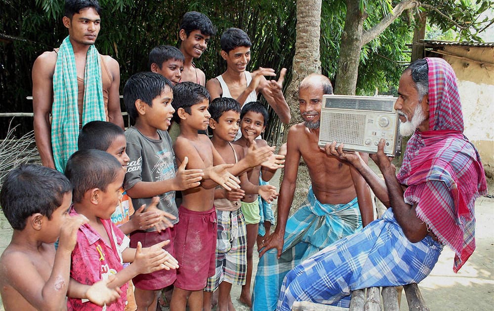 People along with children listen to Prime Minister Narendra Modis radio program Mann Ki Baat at a village in Balughat.