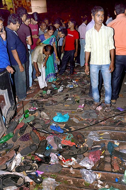 People stand near footwears of stampede victims during Dussehra function at Gandhi Maidan in Patna.