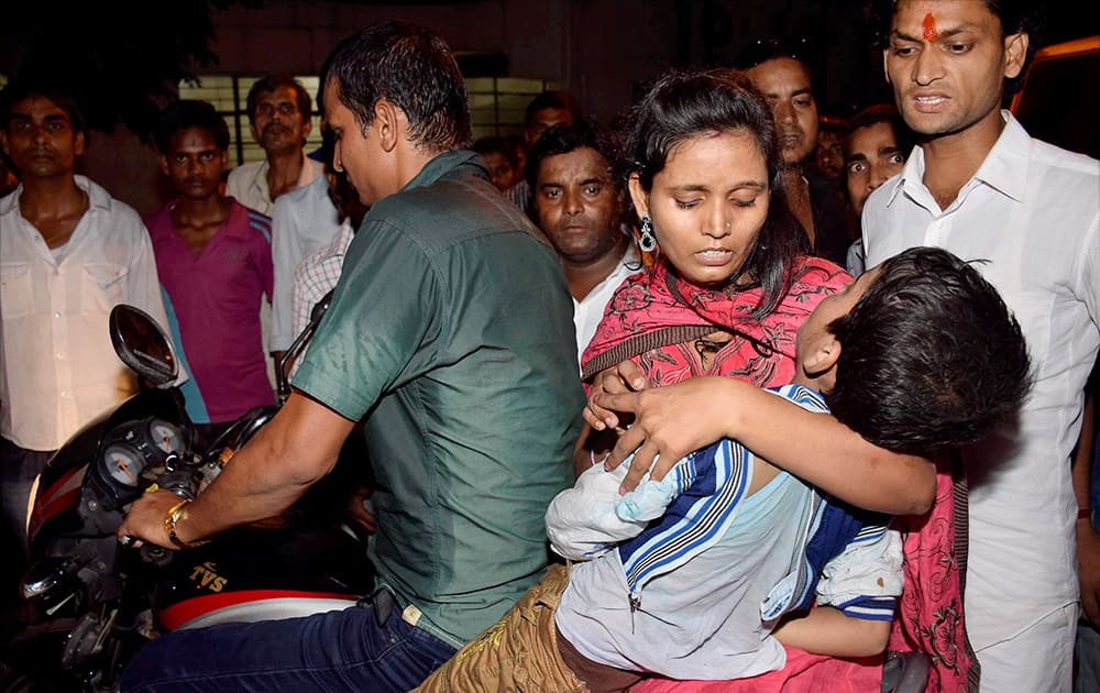 A woman takes an injured kid to hospital after a stampede occured during Dussehra function at Gandhi Maidan in Patna.