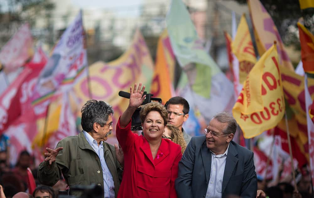 Brazil's President Dilma Rousseff, presidential candidate for re-election of the Workers Party, PT, greets supporters next to Olivio Dutra, PT candidate to the Senate, left, and Tarso Genro, candidate for Governor of Rio Grande do Sul, during a campaign rally in Porto Alegre, Brazil.