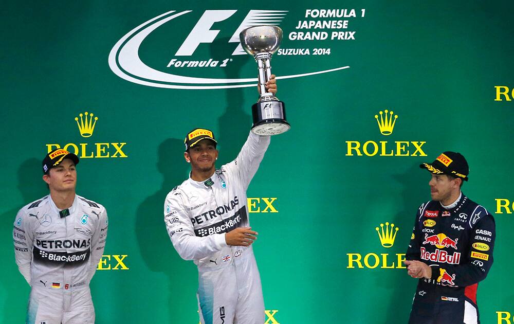 Mercedes driver Lewis Hamilton, of Britain holds up the trophy, with second placed teammate Nico Rosberg and third placer Red Bull Racing driver Sebastian Vettel of Germany during an award ceremony after winning the Japanese Formula One Grand Prix at the Suzuka Circuit in Suzuka, central Japan.