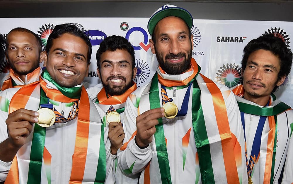 Players of the Asian Games gold medal winner Indian Hockey team with captain Sardar Singh pose with their medals upon arrival at IGI airport New Delhi.