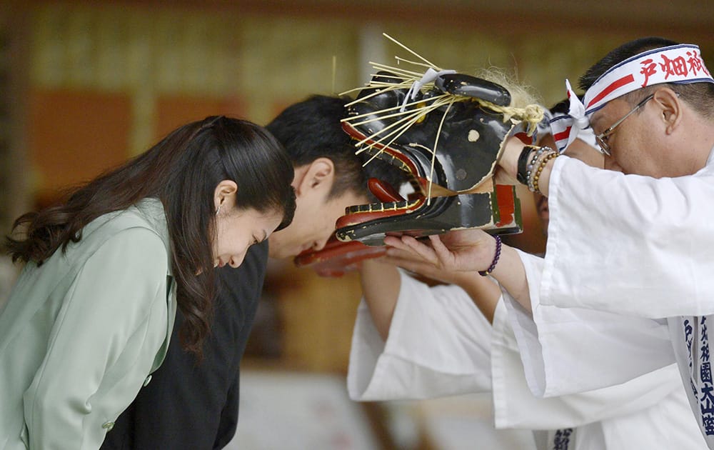 Japan’s Princess Noriko, left, and Kunimaro Senge bow to have their heads bitten by lion masks, wishing their sound health during Shinto rituals following their wedding ceremony at Izumo Taisha shrine in Izumo, western Japan.