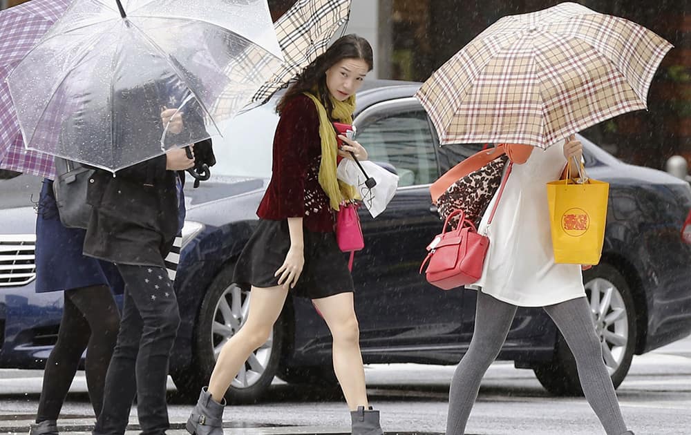 Pedestrians make their way through a street in Tokyo while a powerful typhoon approaches Tokyo.