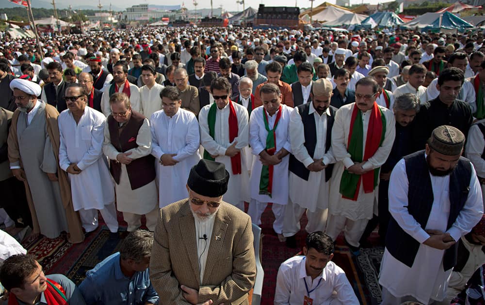 Pakistani Muslim cleric Tahir-ul-Qadri, front, leads the Eid al-Adha, or 'Feast of Sacrifice,' prayers, attended by Imran Khan, behind Qadri with sunglasses, outside a parliament building in Islamabad, Pakistan.