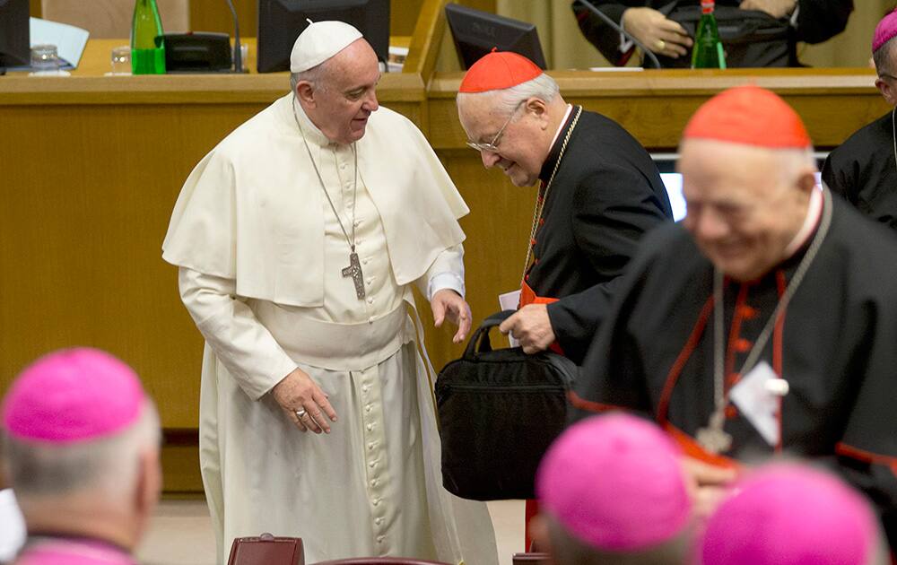 Pope Francis gives a bag to Cardinal Angelo Sodano as he arrives for the afternoon session of a two-week synod on family issues at the Vatican.