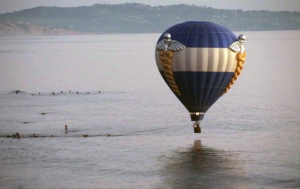 A hot air balloon dips close to the ocean as it is pulled in by surfers in Cardiff-by-the-Sea, a beach community in Encinitas, Calif.