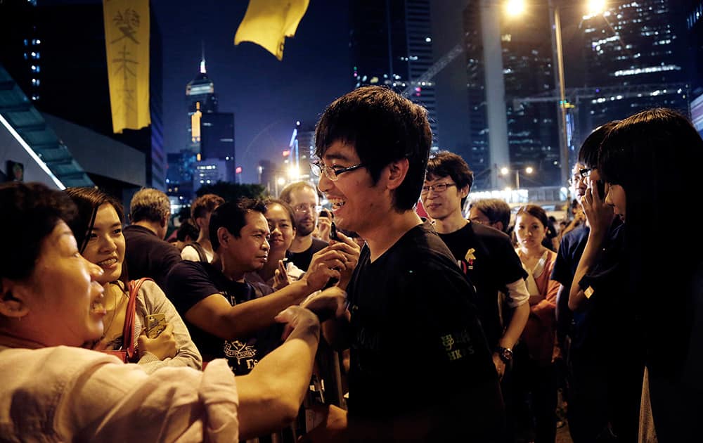 Pro-democracy student leader Alex Chow smiles as supporters encourage him after a rally, in Hong Kong. 