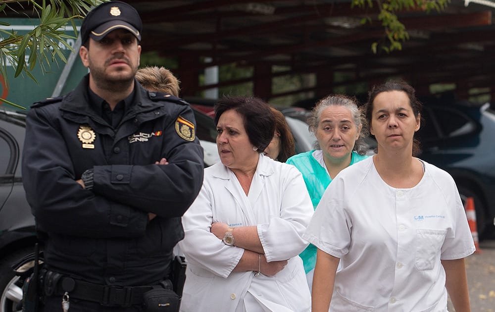 Hospital staff walk out past police guarding the entrance to protest outside the Carlos III hospital in Madrid, Spain, where a Spanish nurse who is believed to have contracted the ebola virus from a 69-year-old Spanish priest is being treated after testing positive for the virus.