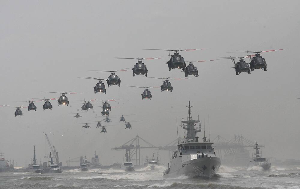 Indonesian Air Force helicopters fly in formation over the fleet of military ships in a show of force during a ceremony commemorating the 69th anniversary of Indonesian Armed Forces in Surabaya, East Java, Indonesia.