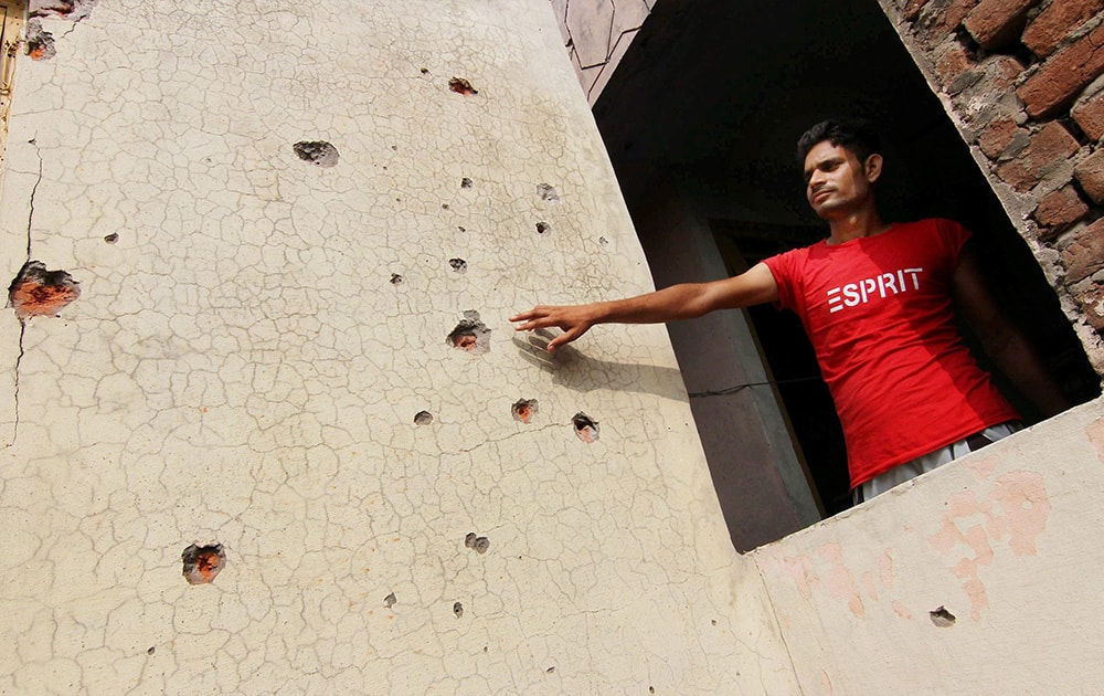 A man shows the bullet marks on a wall after firing from the Pakistani side at Trewa More at Arnia sector in Jammu.