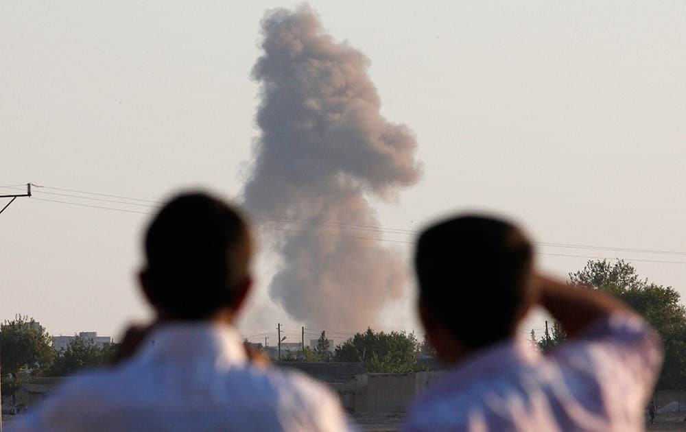 Turkish Kurds standing on the outskirts of Suruc, on the Turkey-Syria border, watch smoke rise following an airstrike in Kobani, Syria, where the fighting between militants of the Islamic State group and Kurdish forces intensified.